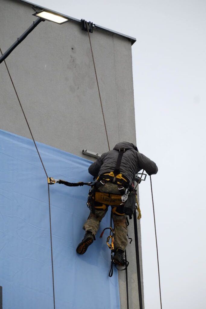 Rope access technician securing a large outdoor banner to a wall, demonstrating safety and skill.